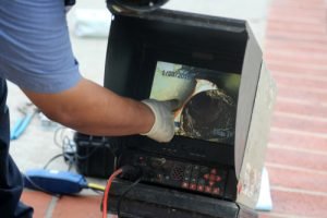Technician using a video inspection camera to examine sewer lines, showcasing plumbing maintenance and diagnostics.