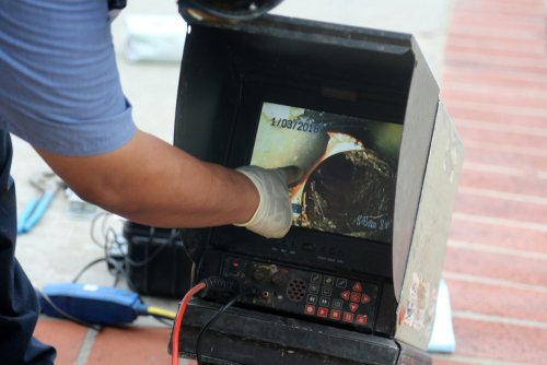 Technician using a video inspection camera to examine sewer lines, showcasing plumbing maintenance and diagnostics.