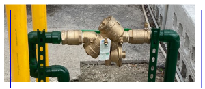 Water backflow prevention system with green and yellow pipes, essential for maintaining clean water supply and preventing contamination in plumbing systems.