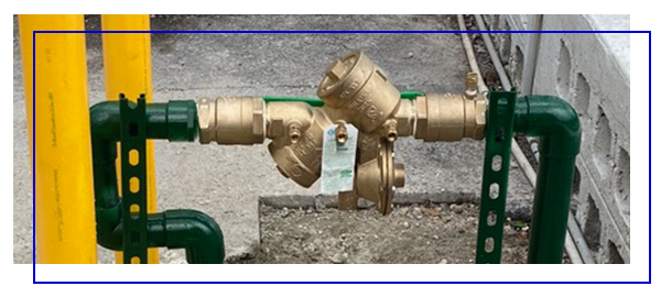 Water backflow prevention system with green and yellow pipes, essential for maintaining clean water supply and preventing contamination in plumbing systems.