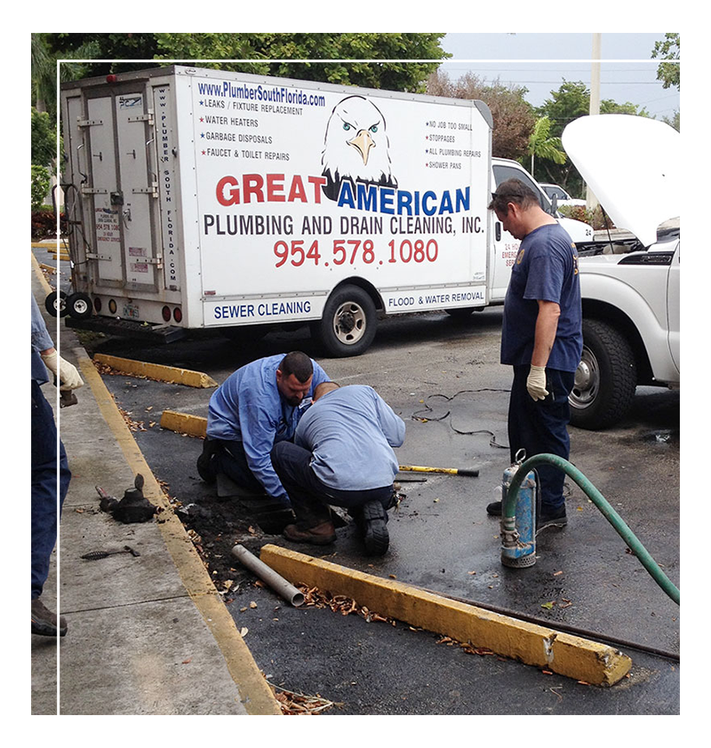 Plumbers from Great American Plumbing performing drain cleaning services in Plantation, FL, alongside service vehicle displaying company branding and contact information.