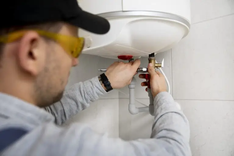 Plumber repairing water heater with tools in residential setting, emphasizing plumbing maintenance and repair services in Broward County.