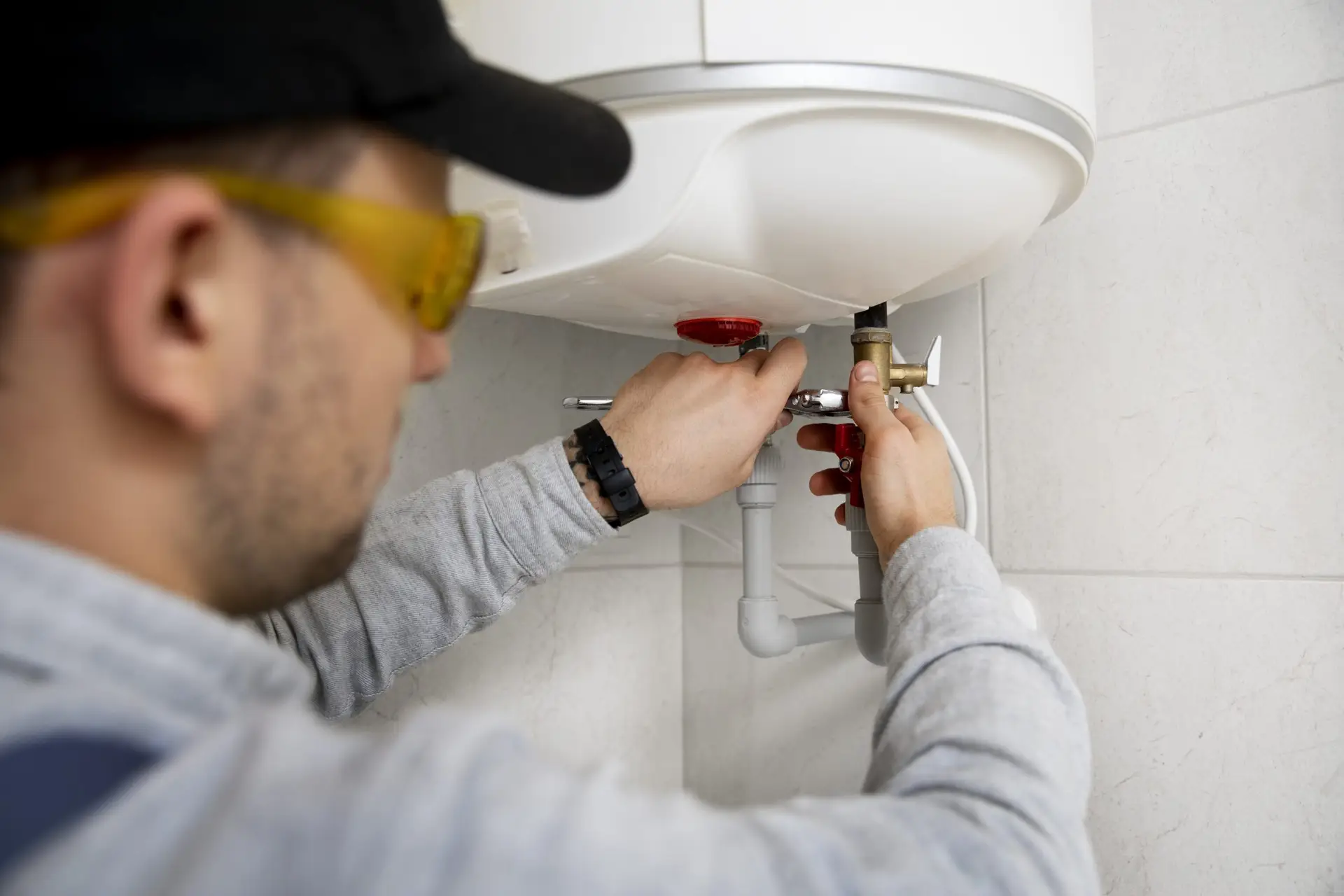 Plumber repairing water heater with tools in residential setting, emphasizing plumbing maintenance and repair services in Broward County.