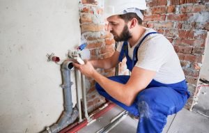 Plumber working on pipe installation in a residential setting, highlighting plumbing maintenance services relevant to older homes in Lazy Lake, Florida.