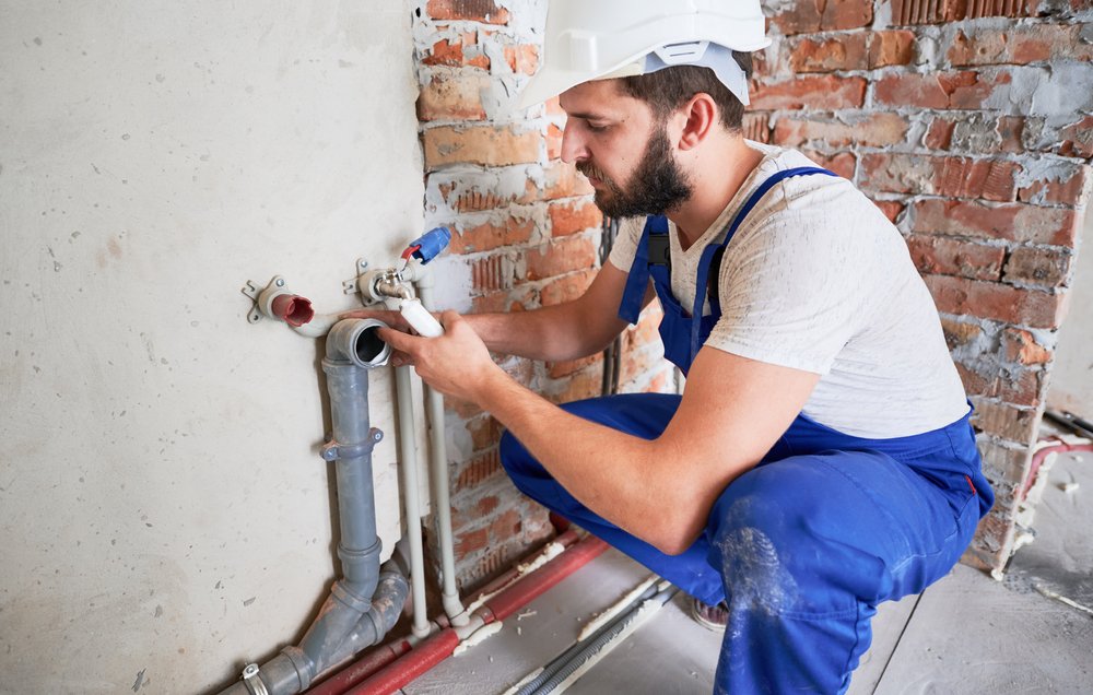 Plumber working on pipe installation in a residential setting, highlighting plumbing maintenance services relevant to older homes in Lazy Lake, Florida.