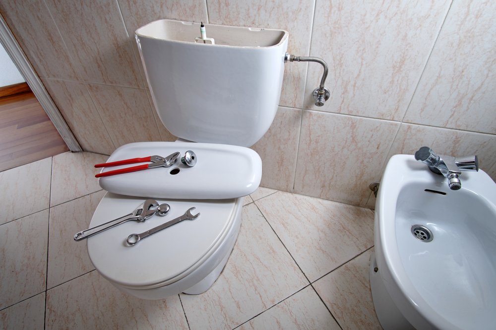 Toilet replacement in Parkland, FL, with plumbing tools and a sink nearby